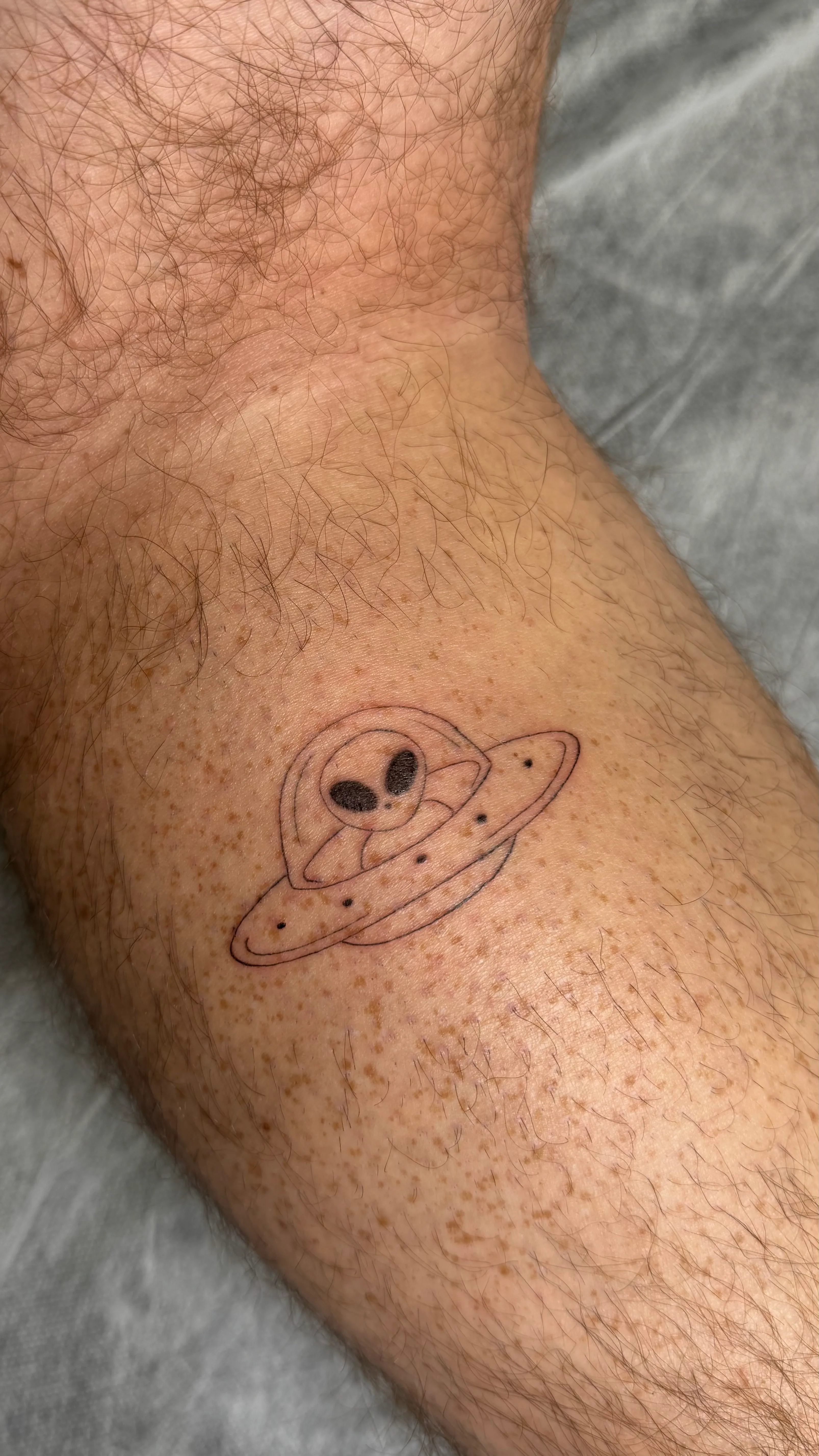 Fijne line-art UFO en alien tattoo